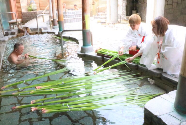 露天風呂にショウブの葉を浮かべる巫女姿の湯郷ベル選手=岡山県美作市で