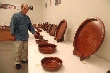 小椋さんと会場に並ぶ鶴山漆器=岡山県津山市で