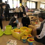 社員の説明を聞きながら商品を手にする保育士ら=岡山県津山市で