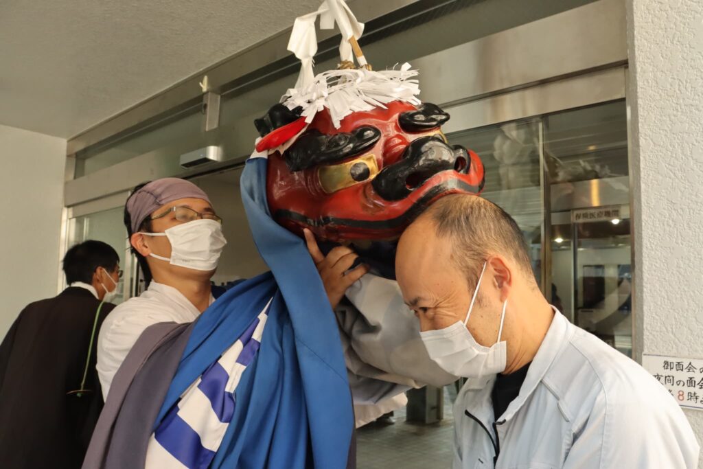 獅子舞にかまれる職員