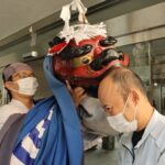 獅子舞にかまれる職員