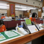 オレンジ色のＴシャツを着て啓発する職員＝岡山県津山市、津山信用金庫本店で