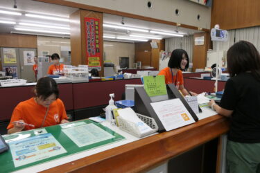 オレンジ色のＴシャツを着て啓発する職員＝岡山県津山市、津山信用金庫本店で