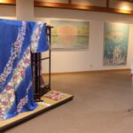 会場に並ぶ染色作品と赤松さん=岡山県津山市で