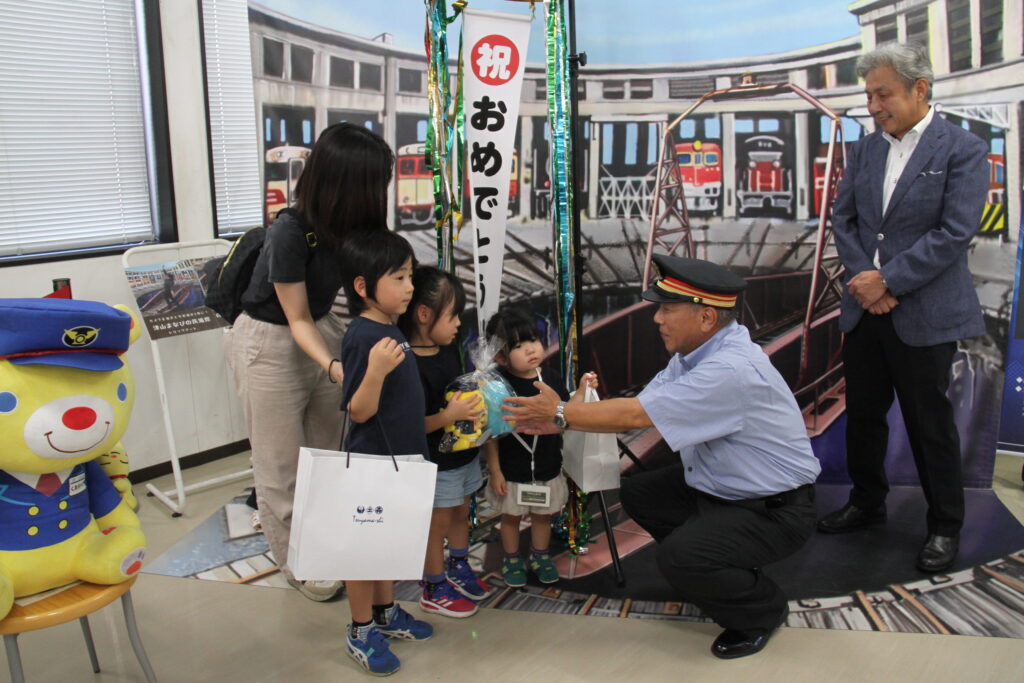 髙橋駅長から記念品を受け取る桝本さん一家