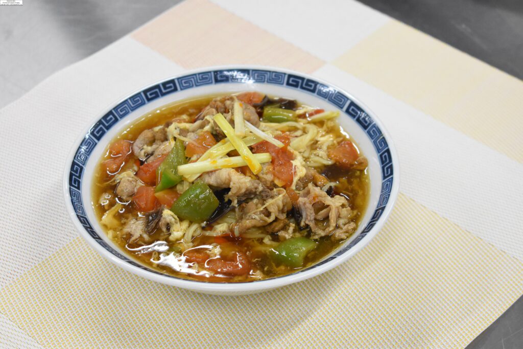 限定販売する学生考案の「桃太郎トマトと赤酢のサンラータン麺」=岡山県津山市で