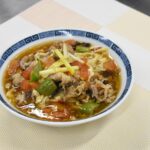 限定販売する学生考案の「桃太郎トマトと赤酢のサンラータン麺」=岡山県津山市で