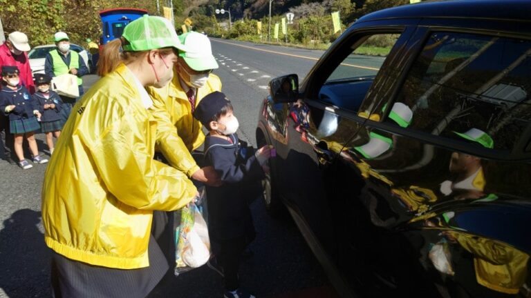 交通安全の願いを込めた梨をドライバーに手渡す園児=岡山県津山市で