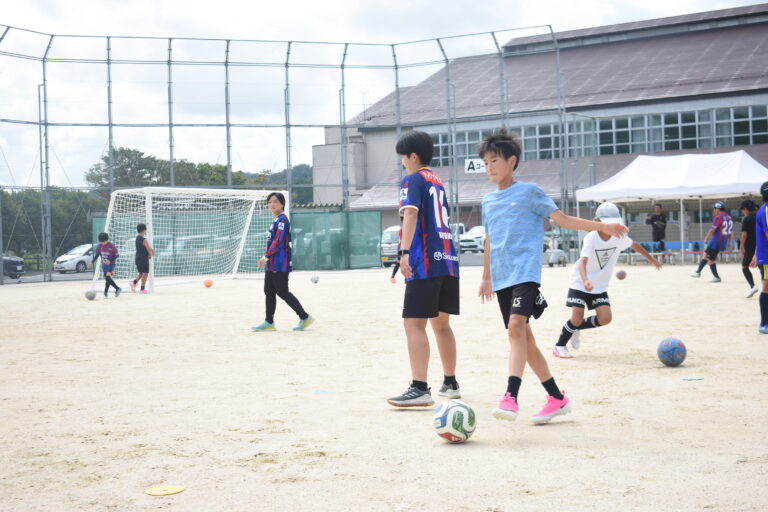 新しいゴールが設置されたグラウンドで、岡山湯郷ベルの選手とサッカーを楽しむ子どもたち＝岡山県津山市で