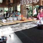 参拝者の名前を組み合わせながら一体の龍を描く田邉さん＝岡山県鏡野町で