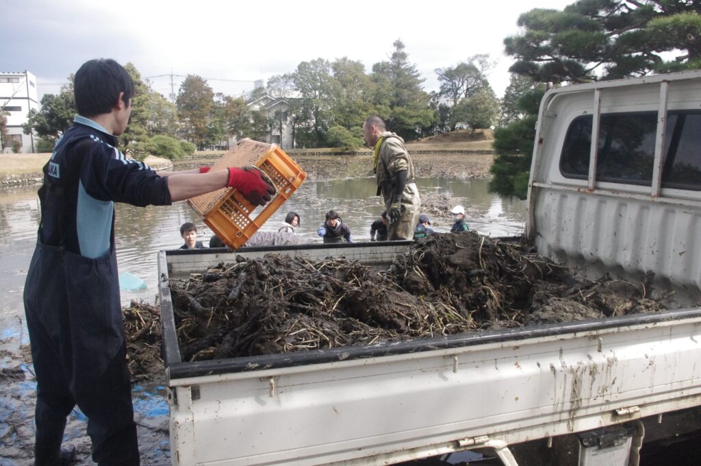 水草と泥を軽トラックに運ぶ参加者