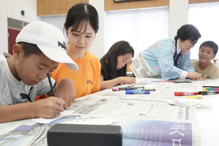 信金職員や学生に手伝ってもらいながら財布をつくる小学生たち=岡山県津山市で