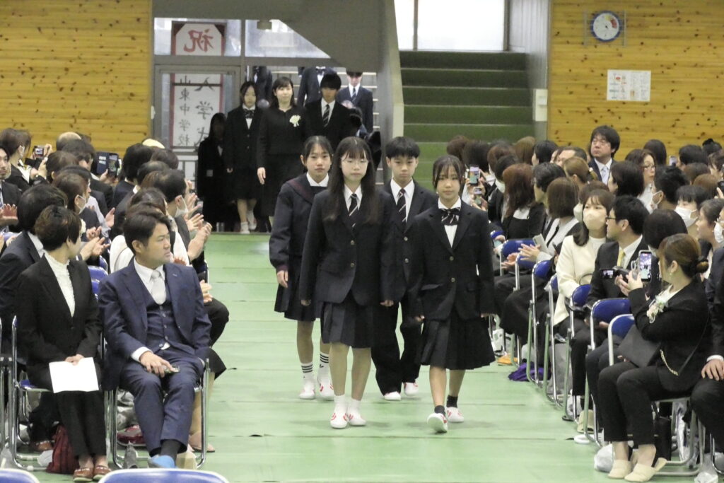 新デザインのブレザーや旧デザインのセーラー服などの制服に身を包み、入場する新入生