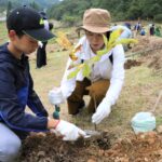 広葉樹の苗木を植え付ける親子連れ=岡山県鏡野町上齋原で