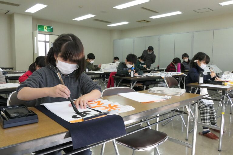 集中して書き初めを行う小中学生たち=岡山県津山市で