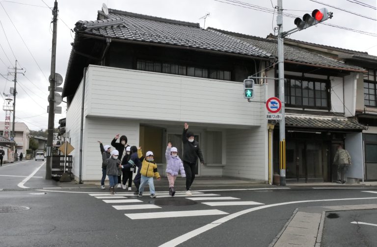 手をあげて横断歩道を渡る園児たち