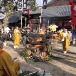 護摩壇に護摩木を投げ入れる僧侶たち=岡山県津山市で