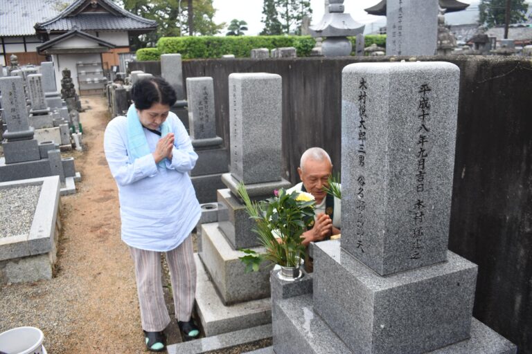 墓前で手を合わせる家族