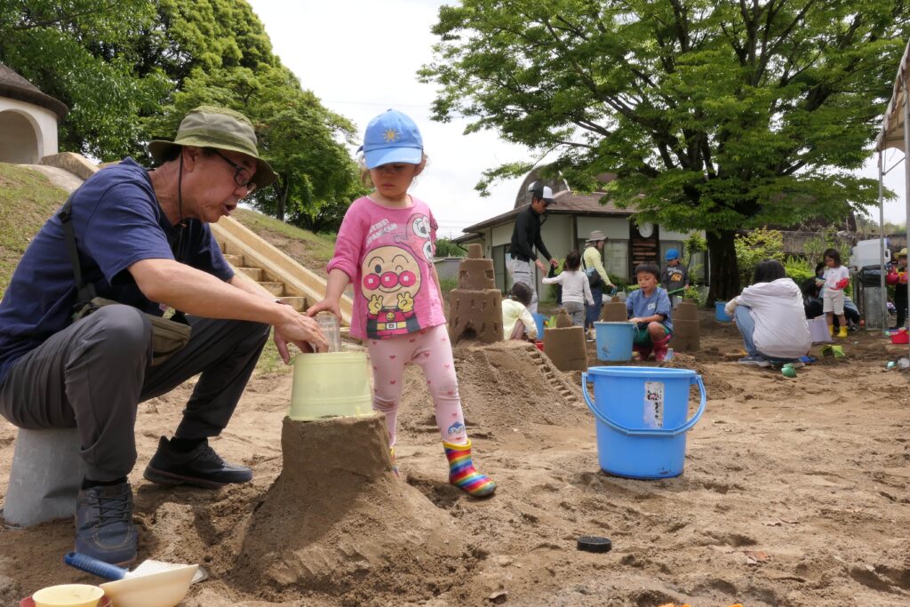 砂の城をつくろうと励む子どもと保護者