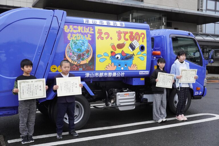 完成したラッピングパッカー車と受賞した児童たち=岡山県津山市で