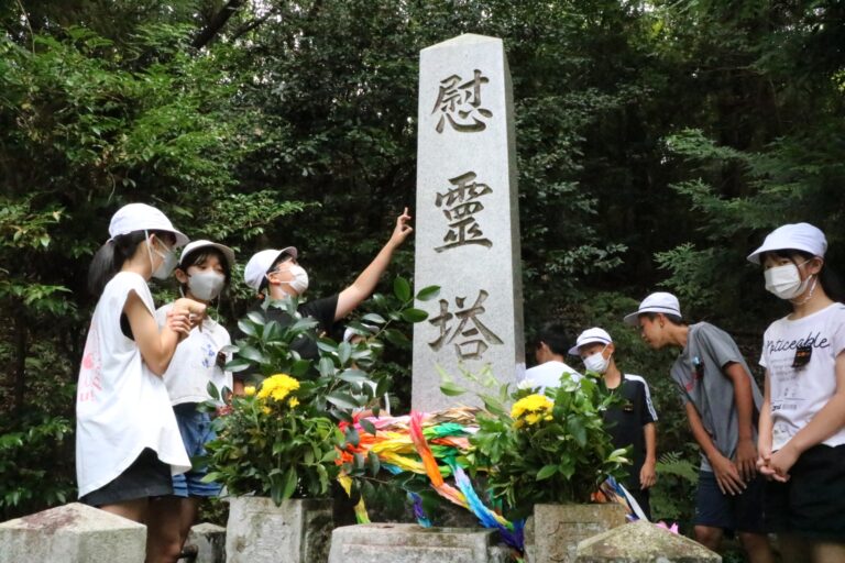 千羽鶴を供えて慰霊塔を見学する児童たち=岡山県津山市で