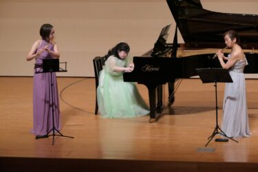 フルートに合わせて優しい音色を紡ぐ川嶋さん（中央）=岡山県津山市で