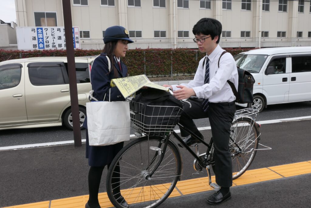 交通指導員の呼びかけに耳を傾ける高校生