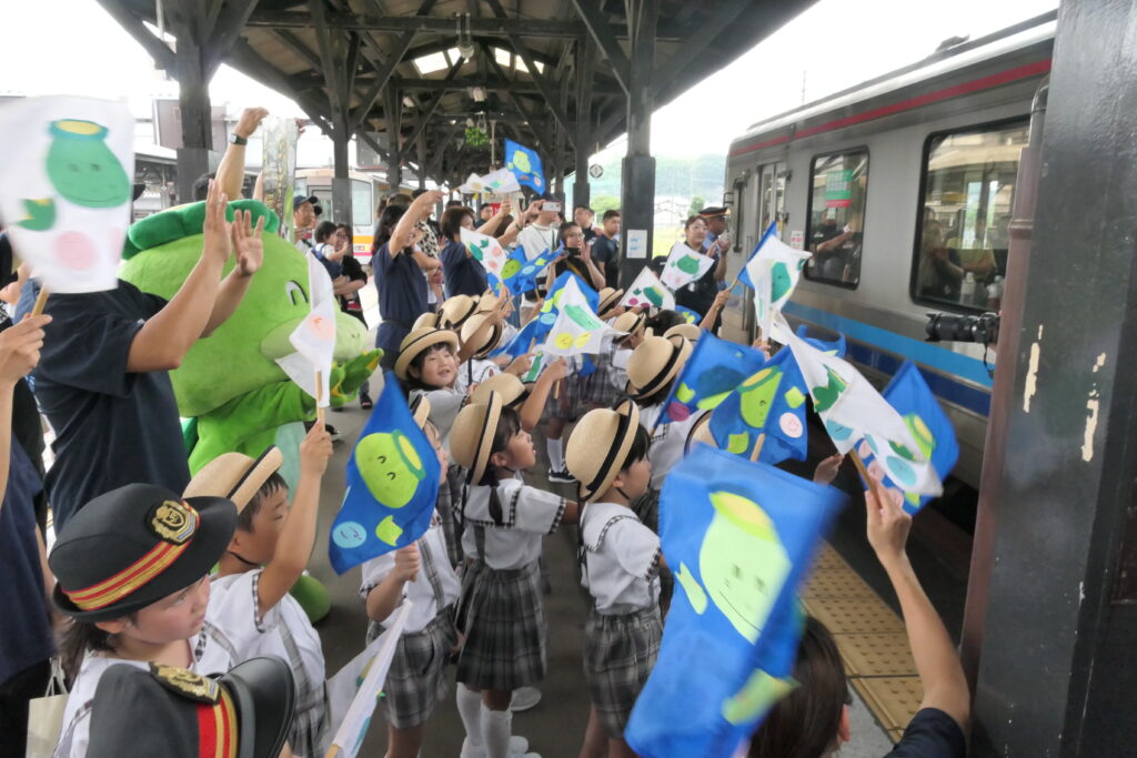 出発する列車を見送るごんちゃんと園児ら