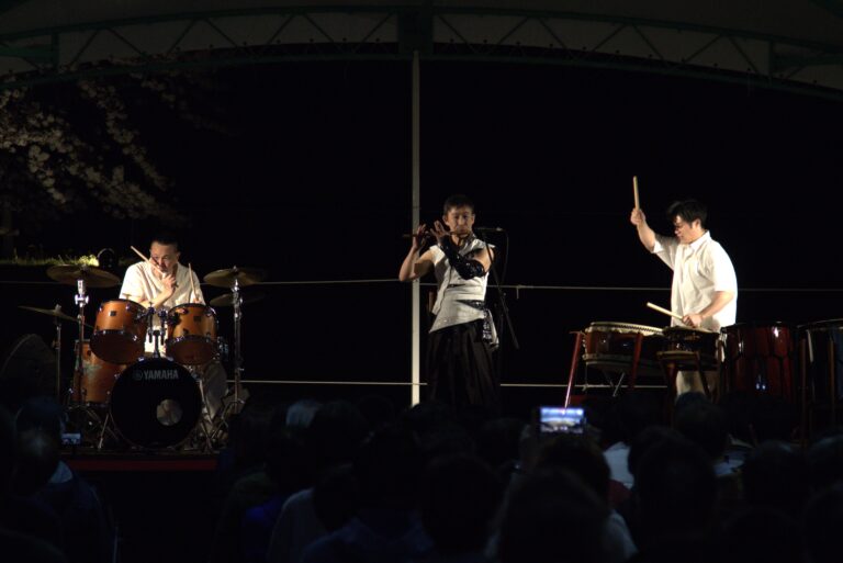 夜桜に囲まれながら演奏する「神鳴KAMI-NARI」の三人。左から、梶原徹也さん、阿部一成さん、坂本雅幸さん。