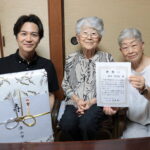 次女の河原さん（右）と光井市長（左）から祝福を受ける倉田さん＝岡山県津山市で