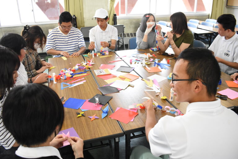 折り紙で輪飾りを作る生徒と学生=岡山県津山市で