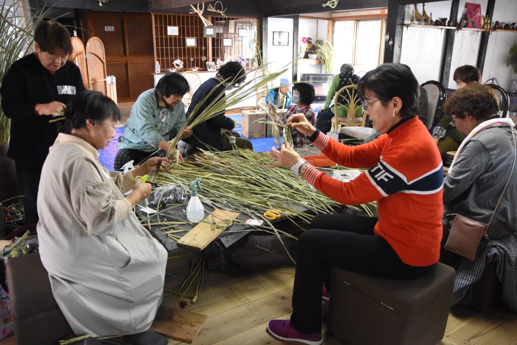 熱心にマコモの飾りづくりに取り組む参加者