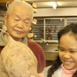 大きなサツマイモを手にする松本さんと細川さん=岡山県津山市で