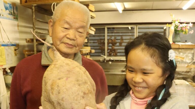 大きなサツマイモを手にする松本さんと細川さん=岡山県津山市で