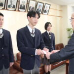 坂手会長に売上金の一部を手渡す森本さん=岡山県津山市で