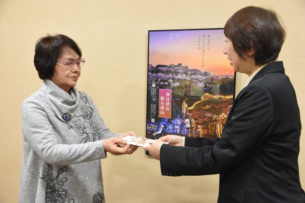 菊入館長（右）にメッセージ入り封筒を手渡す小野田さん