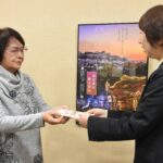 菊入館長（右）にメッセージ入り封筒を手渡す小野田さん