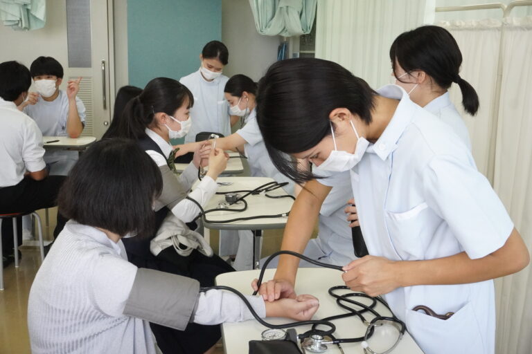 看護体験で血圧測定を教わる参加者=岡山県津山市で