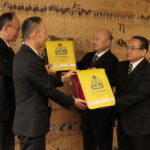 ランドセルカバーを寄贈する石本支部長（右から二番目）と番原理事長（右）=岡山県津山市で