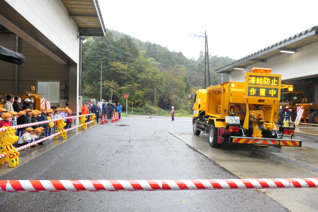 凍結防止剤散布車の作業を見学する園児