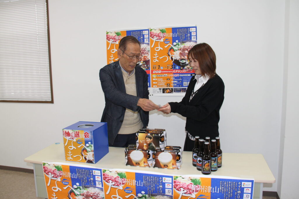 引いたくじを津山市観光協会職員に手渡す今村委員長