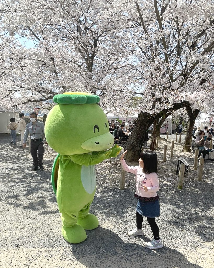 ハイタッチするごんご祭りのキャラクターごんちゃんと少女=2023年4月1日午前10時58分