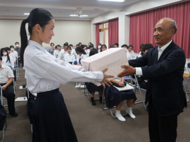 谷西会長から自転車用ＬＥＤライトを受け取る定森さん=岡山県津山市で