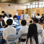 企業のブースで説明を聞く生徒たち=岡山県津山市で
