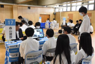 企業のブースで説明を聞く生徒たち=岡山県津山市で