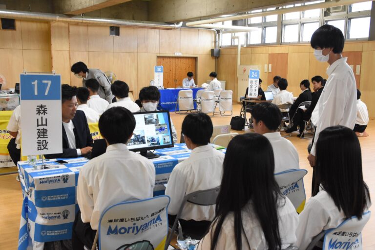企業のブースで説明を聞く生徒たち=岡山県津山市で
