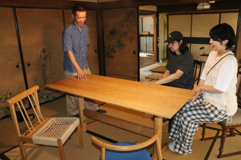 米山さん（左）の創作家具に見入る来場者=岡山県津山市で