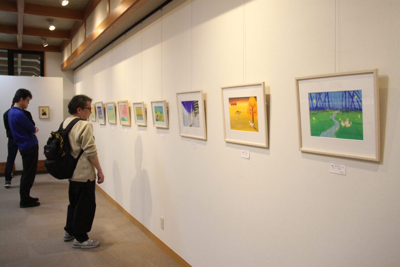 柔らかなタッチのイラストに見入る来場者＝岡山県津山市で