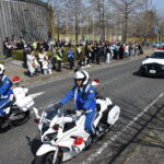 参加者に見送られて広報活動に出発する白バイやパトカー＝岡山県津山市で