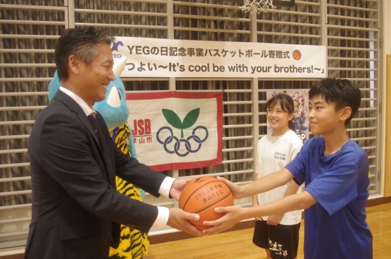 バスケットボールを子どもたちに手渡す宇治会長=岡山県津山市で